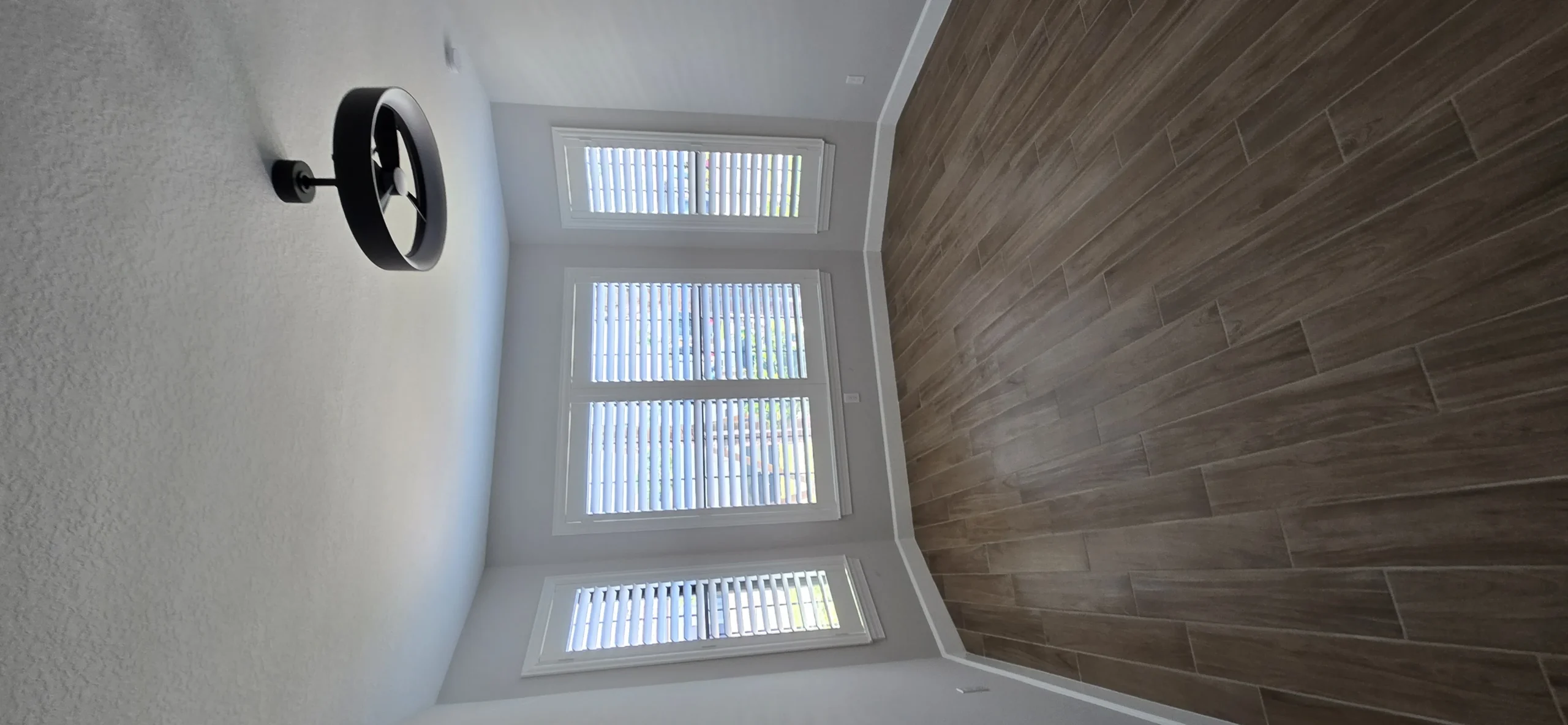 Homeowner maintaining plantation shutters in a bright Florida room, emphasizing cleaning practices
