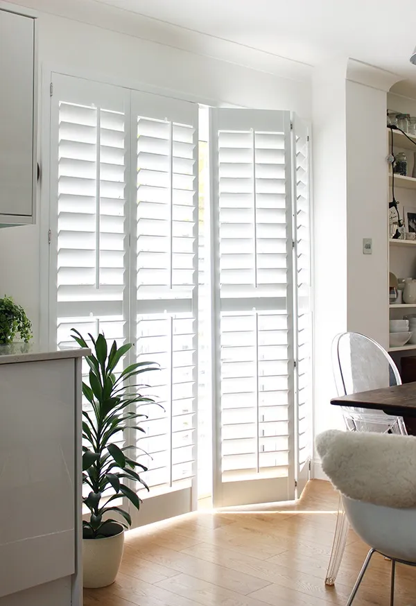 Homeowner cleaning aluminum plantation shutters to enhance durability and longevity