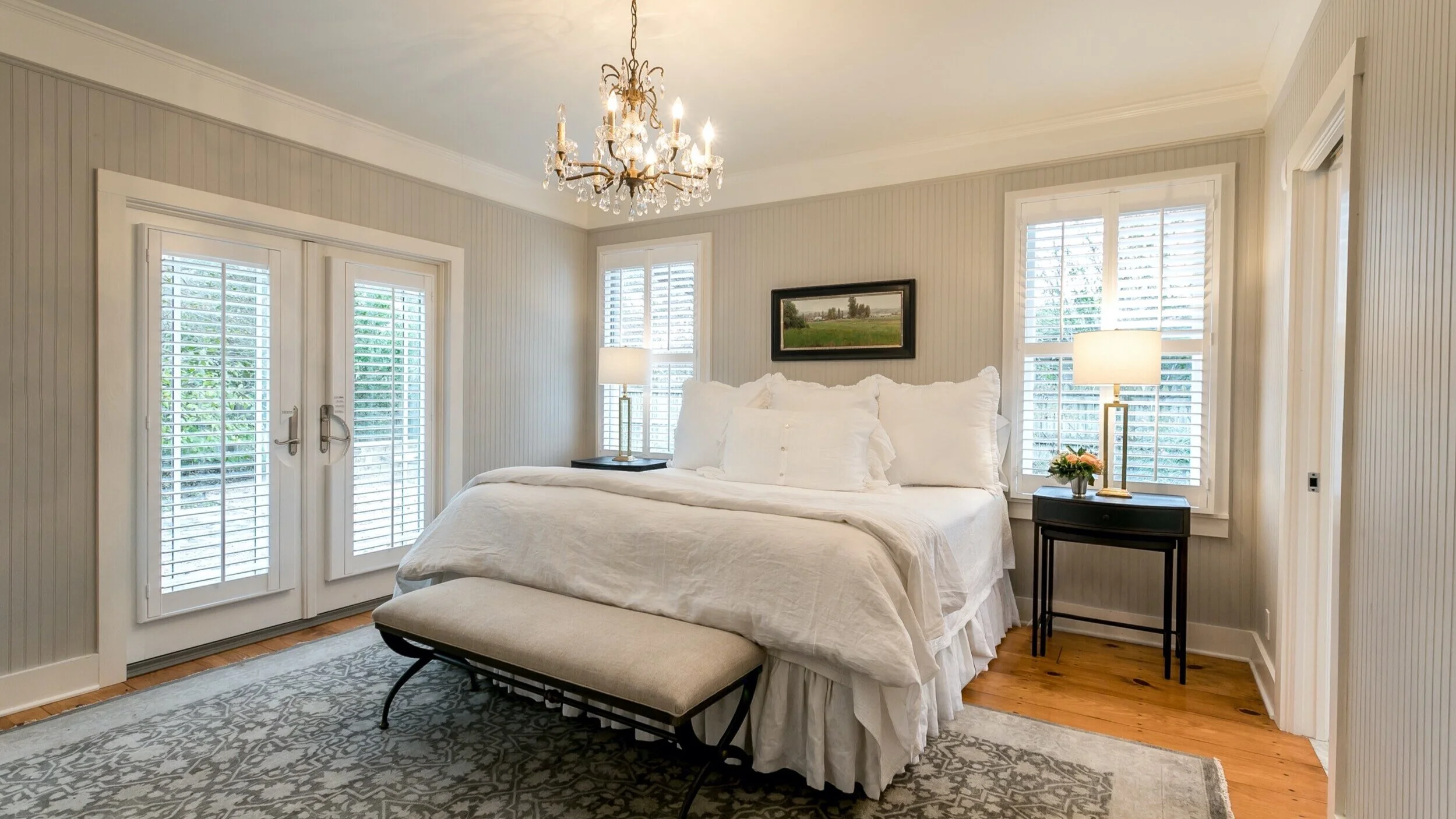 Bedroom interior with white plantation shutters and French doors.