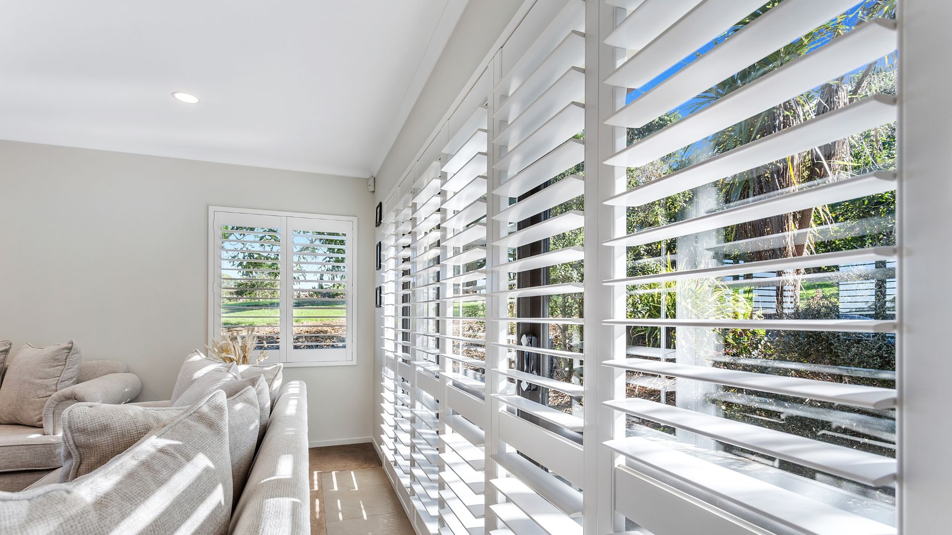 Modern living room with white plantation shutters and natural light.