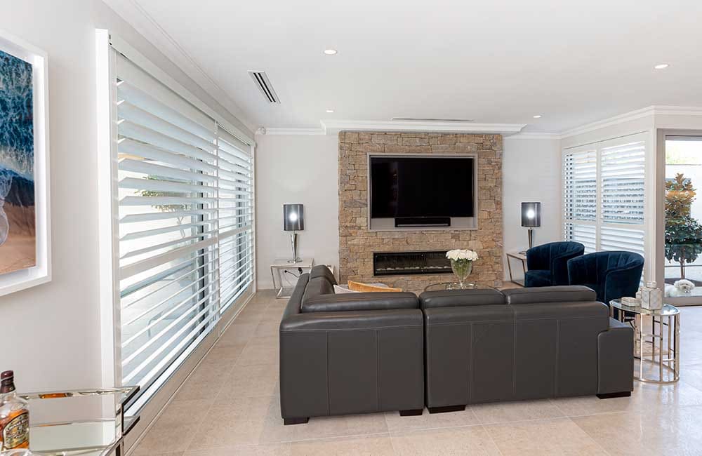 Plantation shutters in Pembroke Pines living room with stone fireplace and modern decor.