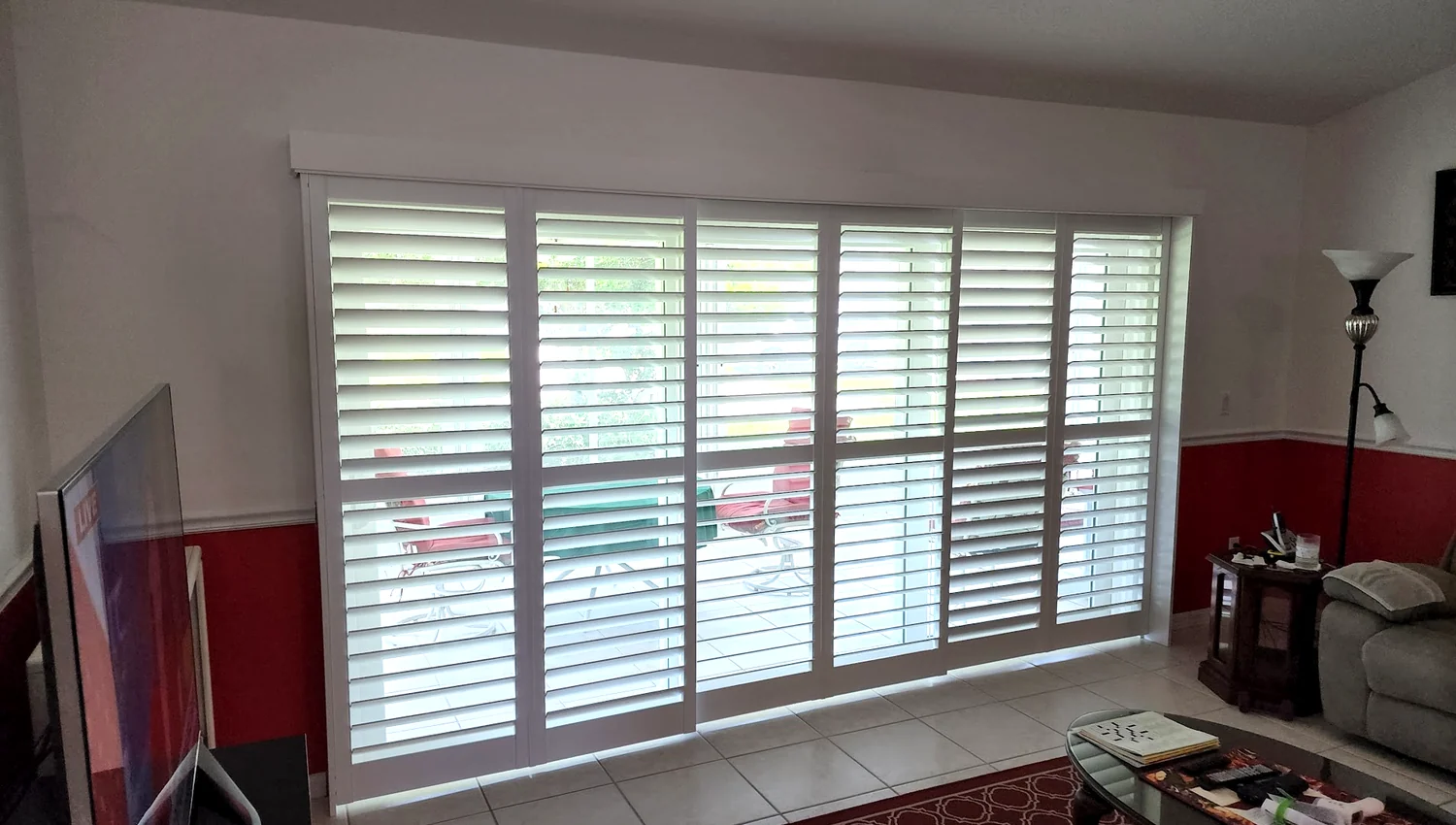 Six-panel plantation shutters covering a large sliding glass door